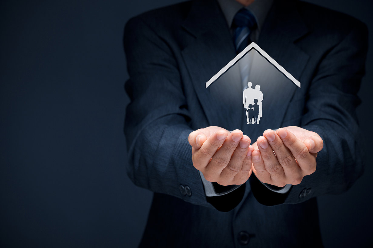 Insurance concept of family life and property insurance family services family policy and supporting families concepts. Businessman with protective gesture and silhouette representing young family and house.