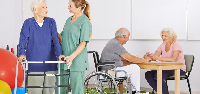 Smiling geriatric nurse with group of senior people in a nursing home